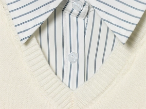 Détail du pull en maille à col en V et chemise rayée bleue pour un look superposé