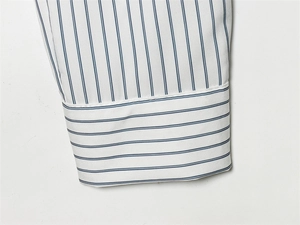 Détail du poignet de chemise rayé bleu et blanc avec motifs de tissus contrastés