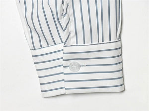 Détail du poignet de chemise à rayures avec motif horizontal et bouton en résine blanc