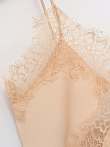 Dettaglio dell'elegante pizzo a ciglia e del tessuto in raso liscio su un top beige