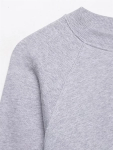 Gros plan d'un sweat-shirt gris clair avec manches raglan et col rond en maille côtelée