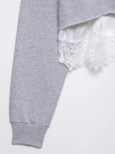 Détail d'un sweat gris avec ourlet en dentelle blanche et poignets côtelés élégants