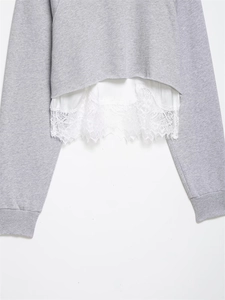 Détail de l'ourlet d'un sweat-shirt gris avec dentelle blanche et coutures précises