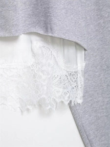 Détail d'un sweat-shirt gris avec ourlet en satin blanc et bordure en dentelle fine