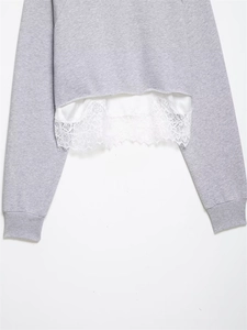 Gros plan détaillé du sweat-shirt gris montrant l'ourlet en dentelle et le satin blanc