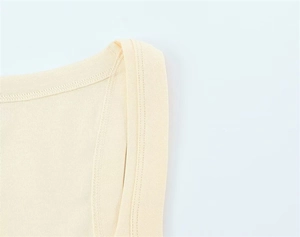 Detailed macro view of reinforced double-needle stitching on beige cotton knit t-shirt