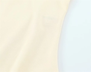 Close-up of pale yellow knitted cotton fabric showing fine texture and clean side stitching