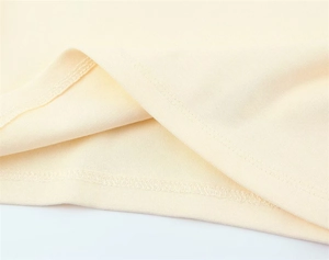 Detail of double-needle stitching and overlock edge on light yellow cotton tank top