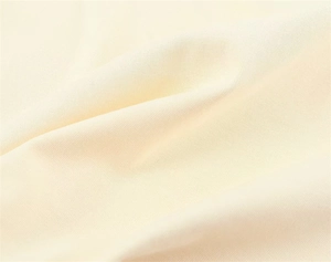 Macro shot of soft cream cotton knit fabric texture with natural drapery folds
