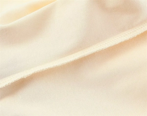 Detailed macro shot showing fine stitching and soft cotton knit fabric in off-white color