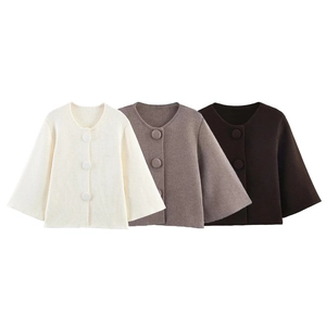 Detailed view of knitted cardigans in beige and brown with large buttons and soft textures