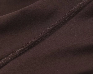 Close-up of overlock stitching detail on high-density chocolate brown knit fabric