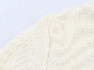 Detailed macro view of the shoulder seam on this off-white knit cardigan for women