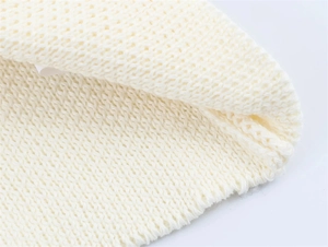 Detailed macro view of soft cream knit fabric and woven label on loose summer cardigan