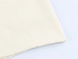 Detailed close-up of cream knit fabric showing fine stitching and smooth finished edges