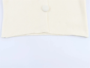 Detailed macro view of the cream knit fabric and matching fabric-covered button closure