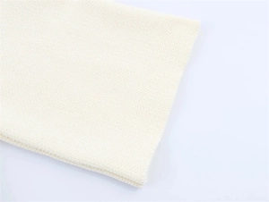 Close-up detail of cream white knitted fabric showing fine mesh texture and edge stitching