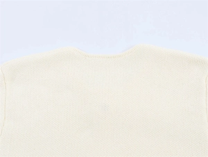 Close-up of the ribbed crew neck and fine knit texture of the cream white cardigan