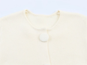 Detail of round neckline and fabric-covered button on cream knitted cardigan jacket