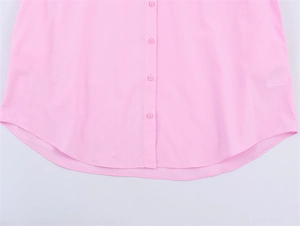 Detail of pink cotton poplin shirt showing button placket and curved hemline