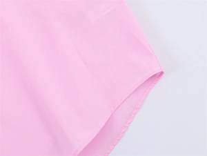 Detailed macro view of the curved hemline and stitching on the pink poplin shirt