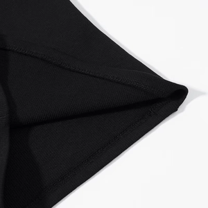 Close-up of high-quality ribbed knit fabric with durable double-stitched hem on black top