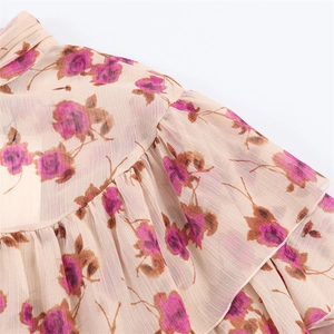Gros plan d'une blouse en mousseline fleurie avec col à volants et motifs de roses vintage