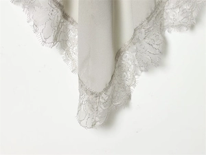 Close-up of light gray georgette fabric with delicate silver floral lace trim detail