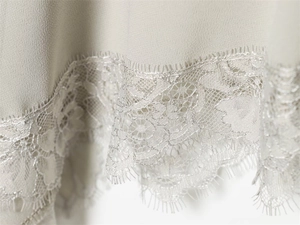Close-up of delicate floral eyelash lace trim on a light sage green georgette top