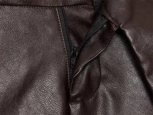 Dettaglio in pelle marrone scuro con texture martellata e chiusura a zip nera liscia