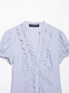 Dettaglio della camicia in popeline a righe blu con volant e profondo scollo a V