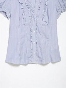 Dettaglio camicia in popeline a righe bianche e blu con volant a strati e scollo a V