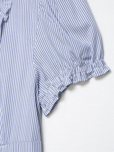 Dettaglio macro dei polsini elastici con ruches su una camicia in popeline a righe bianche e blu