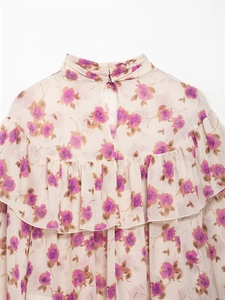 Detail of floral chiffon blouse featuring ruffled high collar and back cutout with metal button