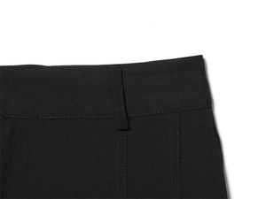 Détail de la taille d'un pantalon noir avec passants de ceinture et coutures précises