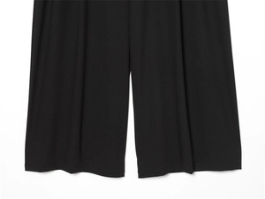 Détail de l'ourlet du pantalon large noir minimaliste avec un tissu au drapé fluide