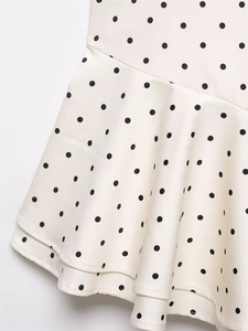 Close-up of the double-layered ruffle hem with black polka dots on cream fabric