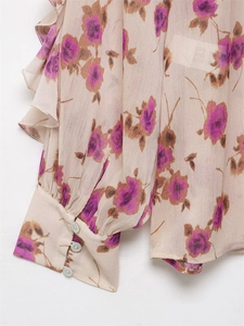 Detailed close-up of floral chiffon fabric with ruffled cuffs and pearl buttons
