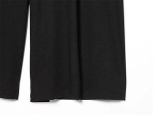 Gros plan du pantalon plissé noir montrant la texture du tissu et la couture du bas