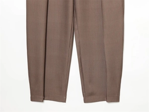 Détail du pantalon ballon marron à fines rayures verticales rouges et design plissé