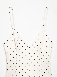 Detail of V-neckline and spaghetti straps on a white polka dot mini dress fabric