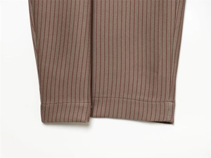 Gros plan du pantalon plissé beige à chevrons montrant la texture du tissu tissé