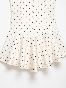 Detailed close-up of double-layer ruffled hem on a white polka dot mini dress