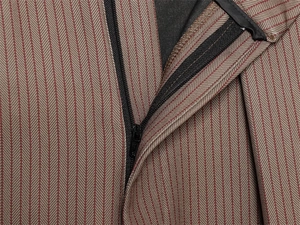 Détail du pantalon ballon plissé brun-rouge montrant la fermeture éclair et le tissu