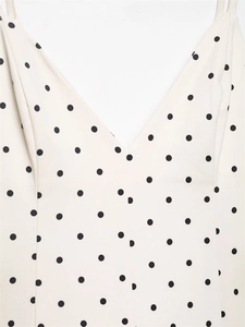 Close-up of V-neckline and polka dot pattern on white summer dress with thin straps