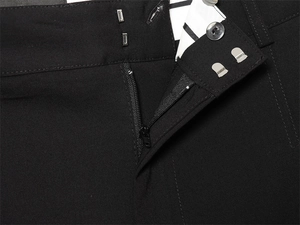 Gros plan détaillé de la fermeture éclair et du crochet sur le pantalon noir plissé