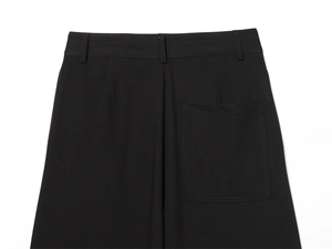 Détail du pantalon noir montrant la poche arrière, les passants et les coutures précises