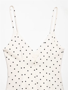 Detailed close-up of V-neck polka dot romper with front zipper and slim straps