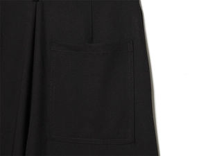 Gros plan détaillé montrant une grande poche plaquée carrée sur un pantalon tissé noir