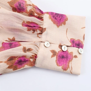 Détail d'un poignet de chemise plissé à imprimé floral et trois boutons blancs sur beige
